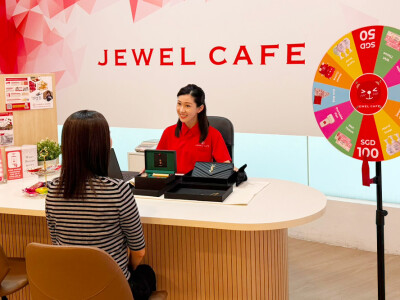A Jewel Cafe staff member assists a customer with a jewelry appraisal at one of the brand's Singapore locations.
