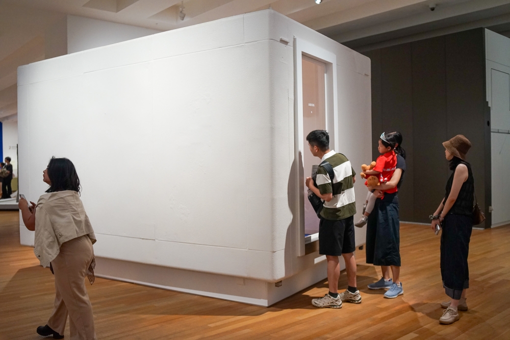 Visitors at M+ peer into the restored Unit A806, an apartment unit which includes a bathroom despite measuring just 255 × 270 × 420 cm. — Picture by Ida Lim