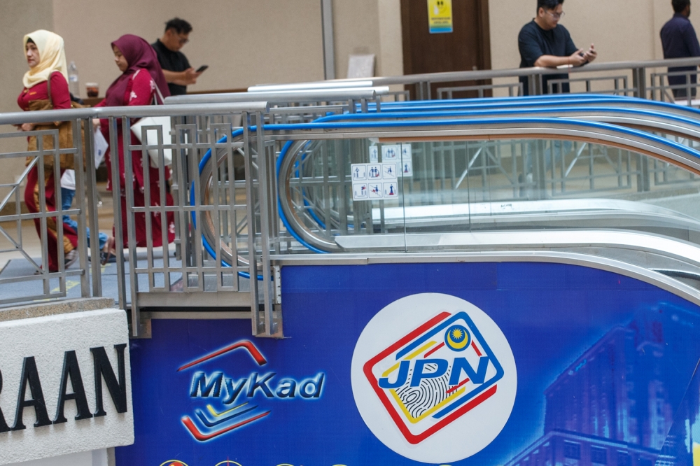 Visitors walk past the MyKad and JPN signage at the National Registration Department (JPN) in Putrajaya, September 23, 2025. — Picture by Raymond Manuel