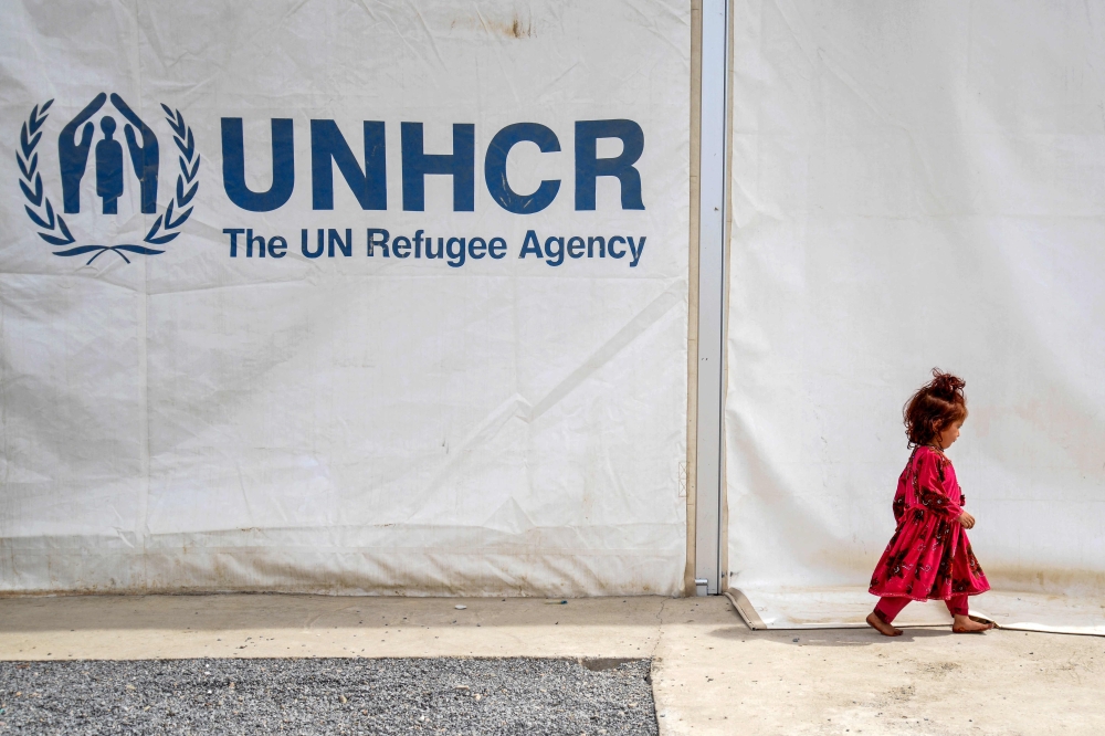 An Afghan refugee girl walks past a registration centre with United Nations High Commissioner for Refugees signage at Takhta Pul district in Kandahar province on April 7, 2025. — AFP pic