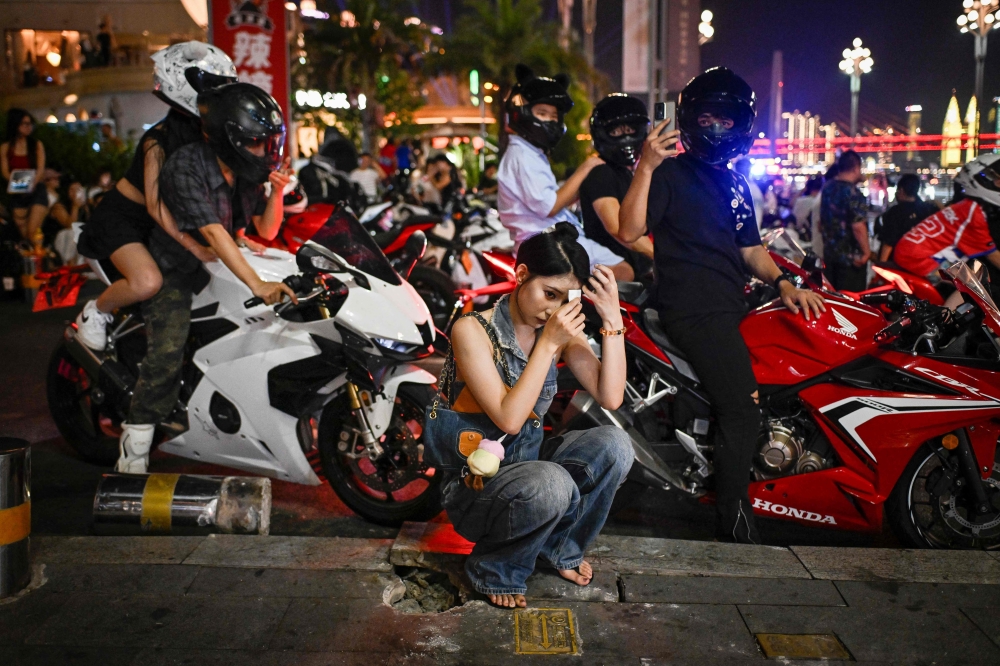 A woman prepares before going for a motorcycle riding photo and video session in Chongqing July 20, 2026. — AFP pic