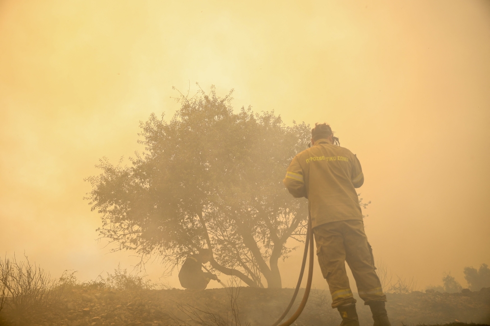 Firefighters attempt to extinguish a wildfire inside a house garden in Loumpa village, west of Athens, on August 2, 2026. — AFP pic