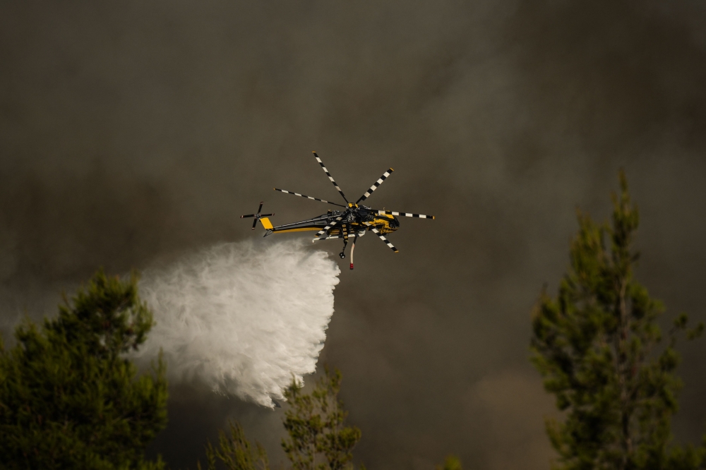 A firefighting helicopter drops water over a wildfire in Porto Germeno, near Athens, on August 2, 2026. — AFP pic