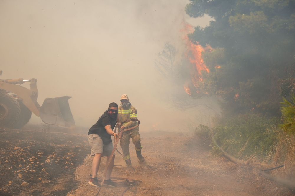 Volunteers and firefighters work to extinguish a wildfire in Veniza, west of Athens, on August 2, 2026. — AFP pic