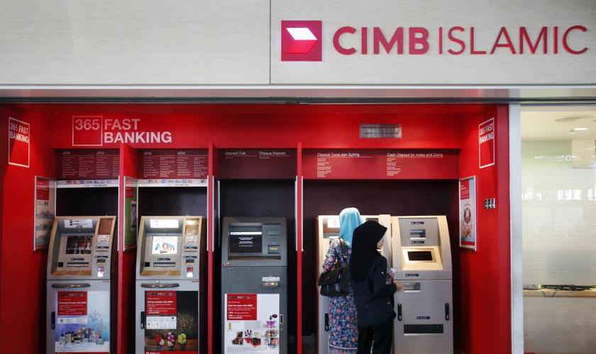 People withdraw cash from an automatic teller machine at a CIMB Islamic branch in Sepang outside Kuala Lumpur. — Reuters pic